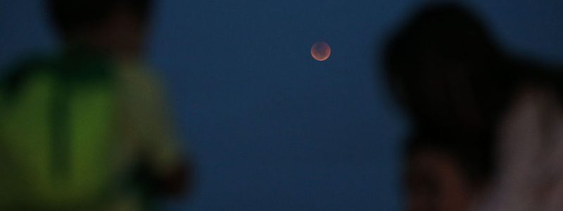 Crianças observam o eclipse total da lua, em que o astro ganha tons avermelhados, conhecido como Lua de Sangue, no Forte de Copacabana.